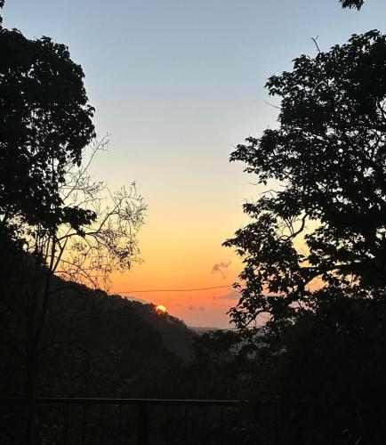 a sunset in the sky with trees in the foreground at Fergust Family Studio Monteverde in Sierra