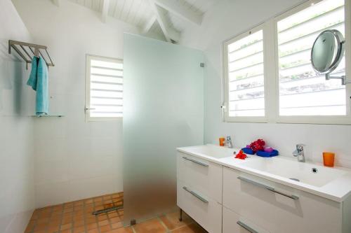 Un baño blanco con lavabo y espejo. en 4bd Villa with Panoramic Sea View and Infinity Pool, en Anse Marcel 