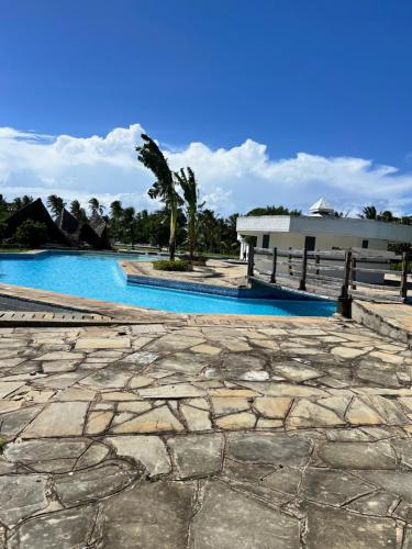 a stone walkway next to a swimming pool at Golden Sun in Diani Beach