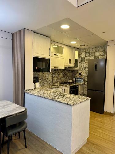 a kitchen with white cabinets and a black refrigerator at Brand New -Very Luxurious 2 Bedrooms Apartment in Ajman