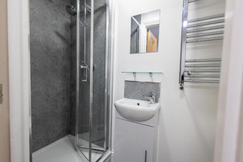 a white bathroom with a sink and a shower at St James Court Aparthotel in Derby