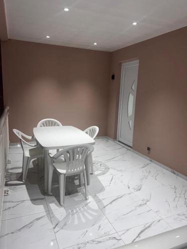 a dining room with a white table and chairs at Le Nid Tropical - T2 Climatisé - Proche du centre in Saint-Joseph