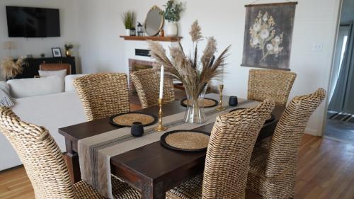 a dining room table with wicker chairs and a table with candles at Cozy chic farmhouse! Perfect for park explorers! in Fresno