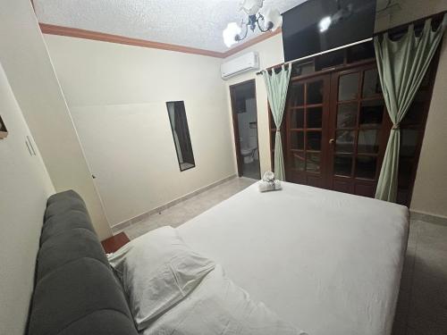 a bedroom with a white bed and a couch at Gaman Hotel Glamping in Santa Cruz de la Sierra