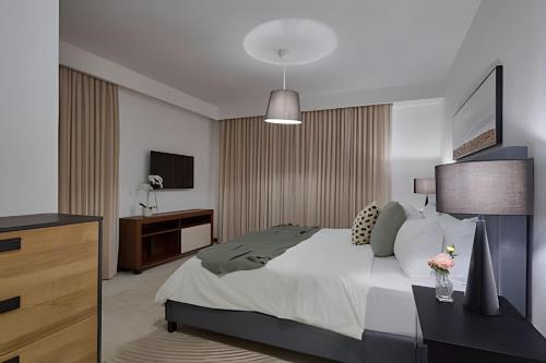 a bedroom with a bed and a dresser and a television at Beachside 1BDR Dreamy Apt.| BBQ + Pool & Sea View in Juan Dolio