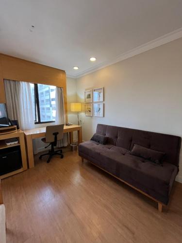 a living room with a couch and a desk at Hotel lindo Aeroporto Congonhas com garagem e piscinas 1703 in Sao Paulo