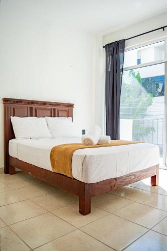 a bed in a bedroom with a large window at Hotel Catedral Jojutla in Jojutla