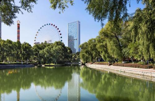 a park with a river and a ferris wheel in the background at Hyatt Regency Changchun in Changchun