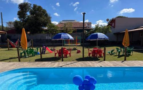 a group of tables and chairs with umbrellas and a pool at Recantto dos pássaros in São Pedro