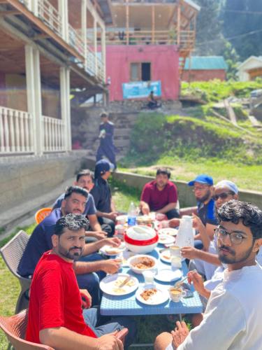 un grupo de hombres sentados alrededor de una mesa comiendo comida en Neelum Resorts Taobat, en Taobat