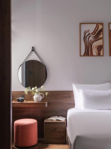 a bedroom with a bed with a mirror and a stool at Scenery Hotel DaLat in Da Lat