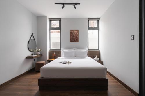 a bedroom with a white bed and two windows at Scenery Hotel DaLat in Da Lat