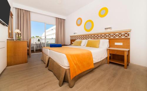 a bedroom with a large bed with an orange blanket on it at Globales Pionero in Santa Ponsa