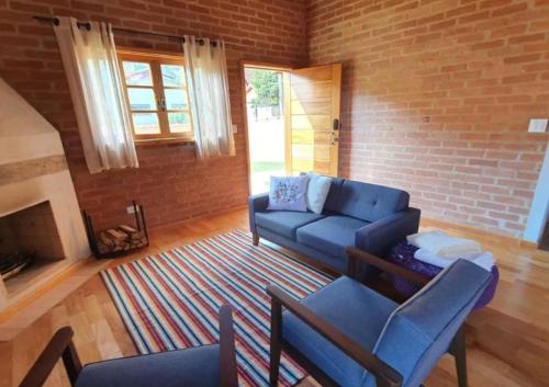 a living room with a blue couch and a brick wall at Villa da Serra - Casa 02 in São Bento do Sapucaí