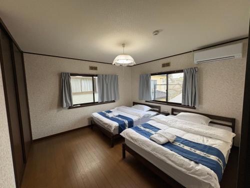 a bedroom with two beds and two windows at 高島市一棟貸切可能貸別荘グループファミリーok 大人数でご利用だとお得連泊がお得BBQ可能自転車無料利用可ペット可 in Takashima