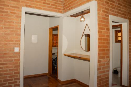 a room with a brick wall and a mirror at Villa da Serra - Casa 02 in São Bento do Sapucaí