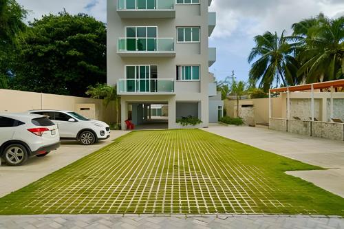 a building with two cars parked in a parking lot at Beachside Heaven Sea View 1bdrm Apartment in Juan Dolio