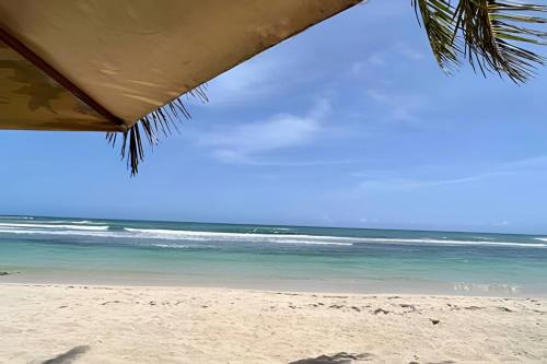 a view of the beach from under a beach umbrella at Beachside Heaven Sea View 1bdrm Apartment in Juan Dolio