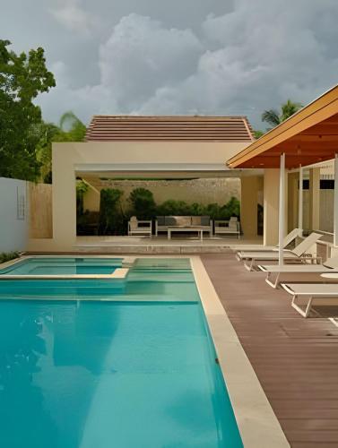 a swimming pool with chairs and a house at Beachside Heaven Sea View 1bdrm Apartment in Juan Dolio