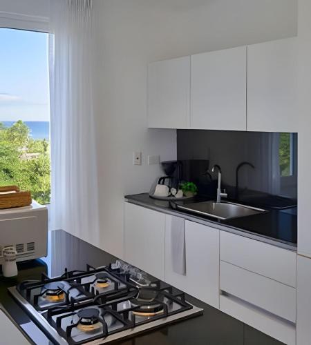 a white kitchen with a stove and a sink at Beachside Heaven Sea View 1bdrm Apartment in Juan Dolio