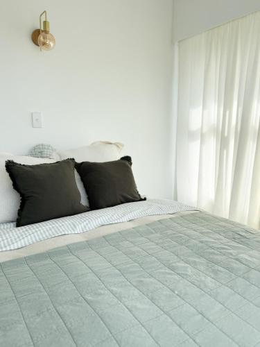 a white bedroom with a bed with black pillows at Nellies Nest in Dargaville