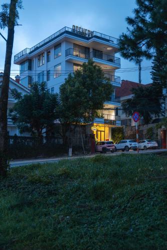 a white building with cars parked in front of it at Scenery Hotel DaLat in Da Lat
