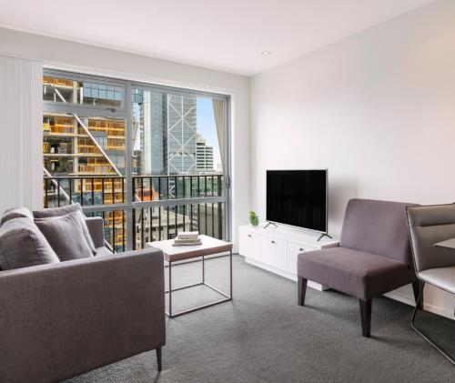 a living room with a couch and a television at Auckland Harbour Suites in Auckland