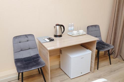 two chairs and a wooden table with a tea kettle on it at Belon Garden Hotel in Prigorodnyy