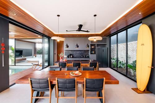 a dining room and kitchen with a wooden table and a surfboard at Luxury 2-Bedroom Villa with Private Pool - Uluwatu in Ungasan