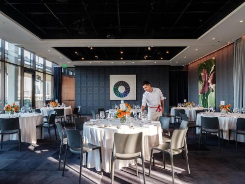 a man standing in a dining room with tables at The Loren Hotel Austin in Austin