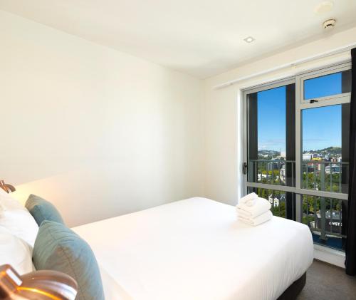 a bedroom with a white bed and a large window at Auckland Harbour Suites in Auckland