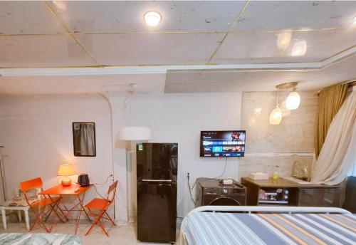 a room with a bed and a table and a refrigerator at Homestay Hostel Apartment Minh Lộc in Ho Chi Minh City