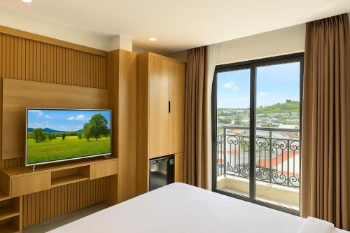 a bedroom with a flat screen tv and a large window at Amory Dalat Hotel in Khu Chi Lăng
