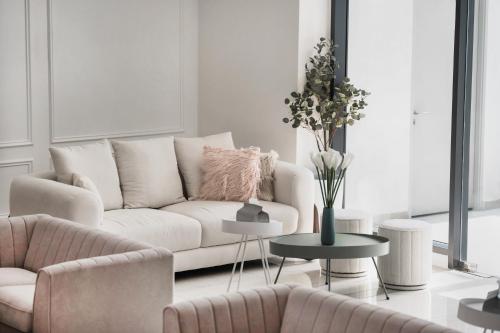 a white living room with a white couch and tables at FOX Hotel Glenmarie Shah Alam in Shah Alam