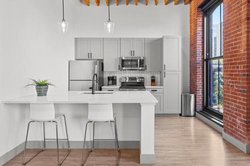 a kitchen with white cabinets and a counter with stools at Brick & Bed Riverfront Lofts, G 203 in Saint Louis