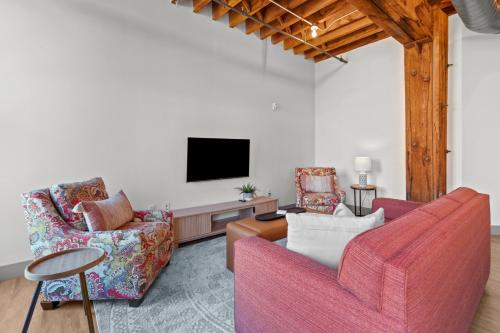 a living room with two chairs and a flat screen tv at Brick & Bed Riverfront Lofts, G 301 in Saint Louis