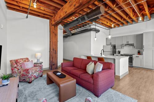 a living room with a red couch and a kitchen at Brick & Bed Riverfront Lofts, G 301 in Saint Louis