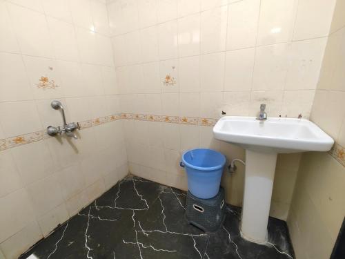 a bathroom with a sink and a blue bucket at Hotel Sskar Executive in Pune