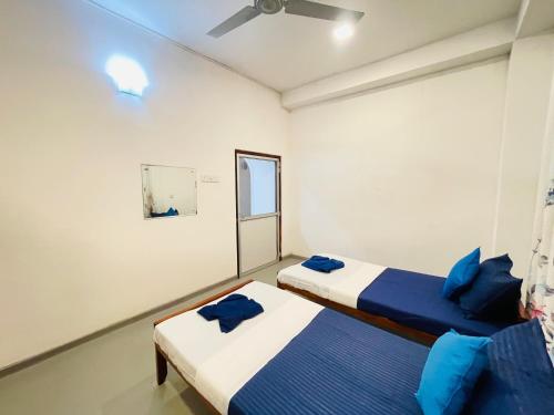 two beds in a small room with blue pillows at Kenashi Green Villa in Weligama