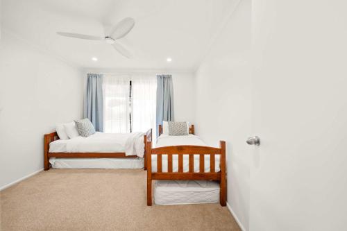 a bedroom with two beds and a ceiling fan at Wurtulla Seabreeze Sanctuary - Pool Spa & PF in Kawana Waters