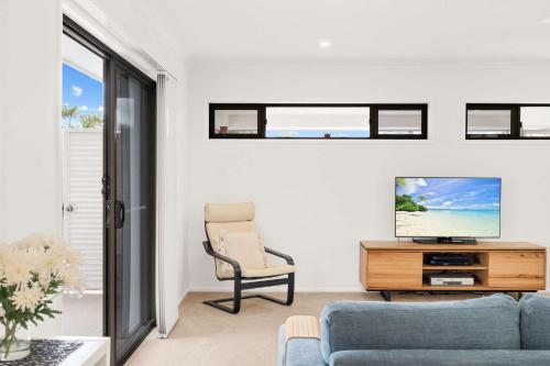 a living room with a blue couch and a tv at Wurtulla Seabreeze Sanctuary - Pool Spa & PF in Kawana Waters