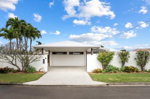 a white house with a garage and palm trees at Wurtulla Seabreeze Sanctuary - Pool Spa & PF in Kawana Waters