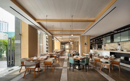 a restaurant with tables and chairs and a kitchen at Mumian Shenzhen Luohu JDV by Hyatt in Shenzhen