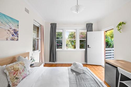 a white living room with a bed and windows at Courtyard Double Room - Next to Transport & Shops in Killara - Shared Bathroom in Killara