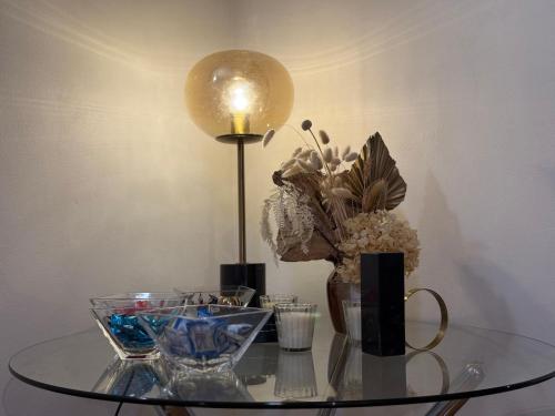 a glass table with a lamp and a vase of flowers at The Grand Book Nook Retro Stay - Luxury King mattress with Flat TV - Private walk in book lounge & Study in Sydney