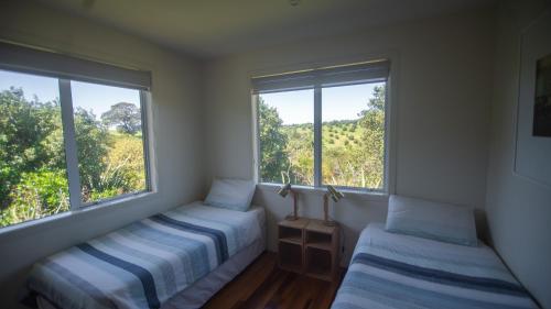 two beds in a room with two windows at Rotoroa Island Wildlife Sanctuary in Auckland