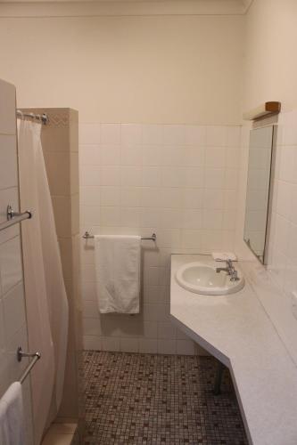 a white bathroom with a sink and a mirror at Palm and Pawn Motor Inn in Wagga Wagga