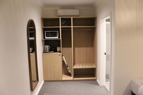 a room with a cupboard with a microwave and a microwave at Palm and Pawn Motor Inn in Wagga Wagga