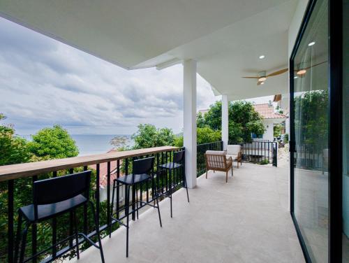 a balcony with chairs and a view of the ocean at Sea Breeze Home in Haad Yao