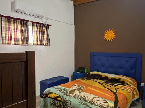 Un dormitorio con una cama con cabecero azul. en COMPLEJO AyH, en Malagueño